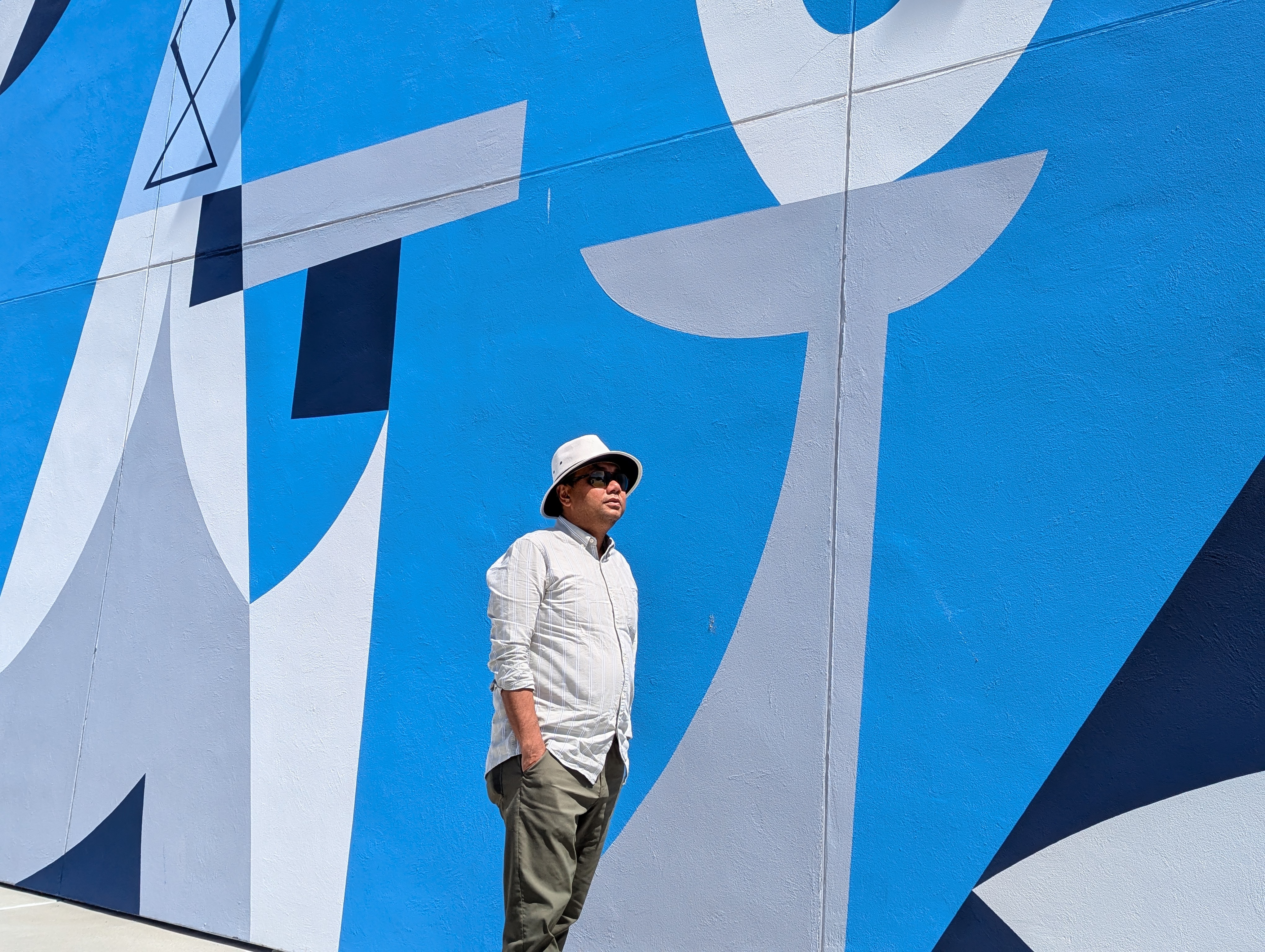 Subhasis Dasgupta standing beside a blue mural